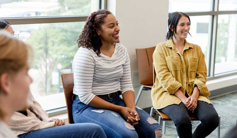 Happy group of peers at group therapy talking and laughing