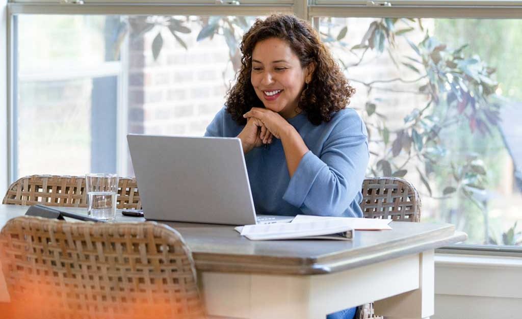 Happy mature woman learning online with laptop