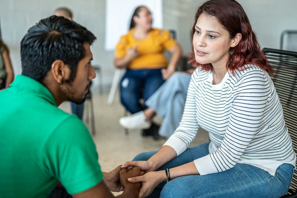 Young woman at grief counselling session talking to man about loss