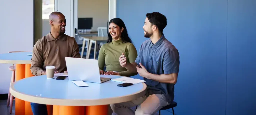 Diverse group of business people laughing while working on a laptop at work