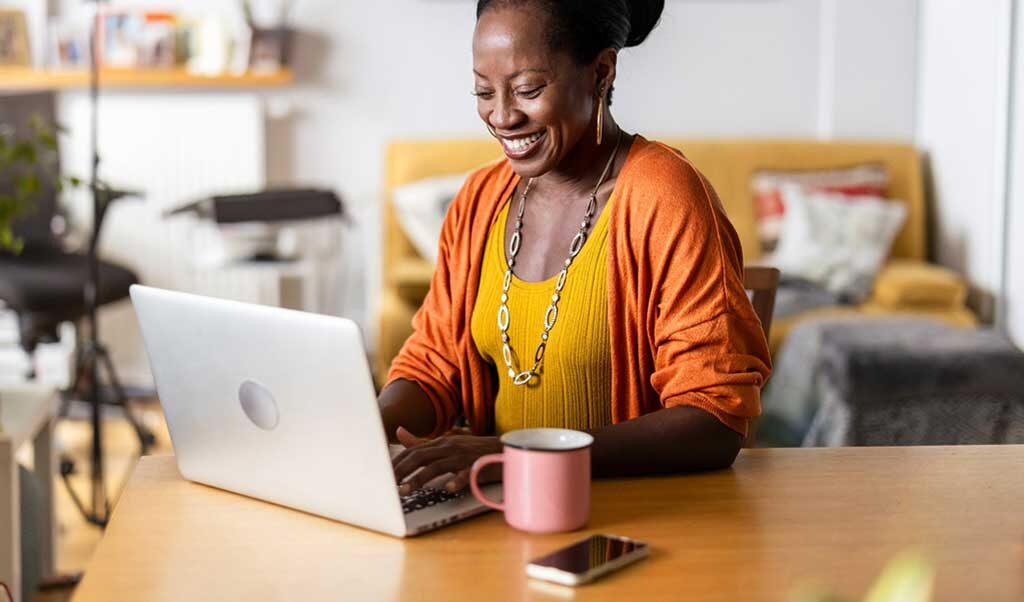 A women sitting in her home working in front of her laptop