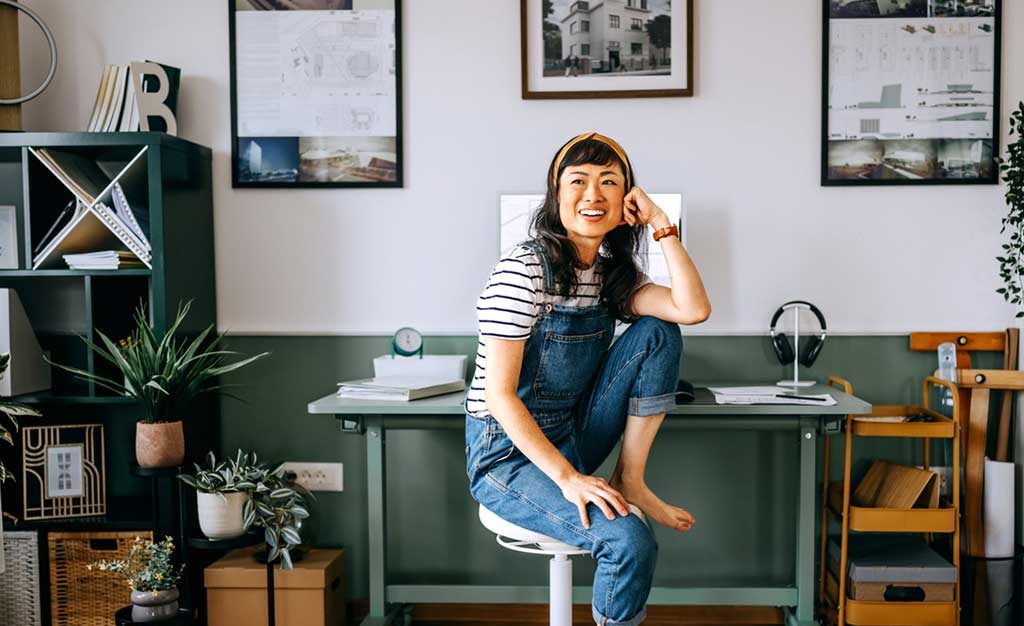 
		Portrait of cheerful casually clothed beautiful woman sitting at the desk at home office stock		
